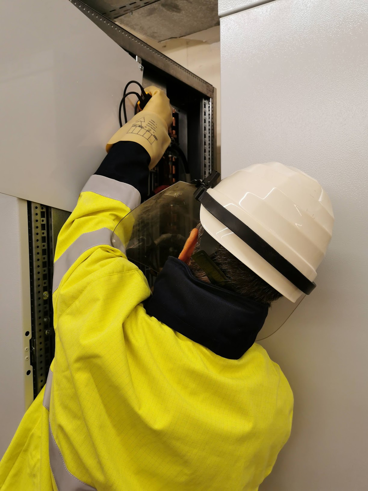 Elektrofachmann arbeitet mit Schutzausrüstung an einer Niederspannungs-Schaltanlage